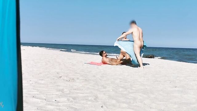 Два парня и девушка устроили групповой секс на нудистском пляже