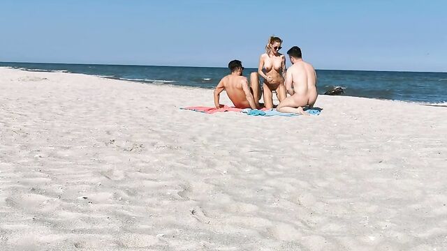 Два парня и девушка устроили групповой секс на нудистском пляже